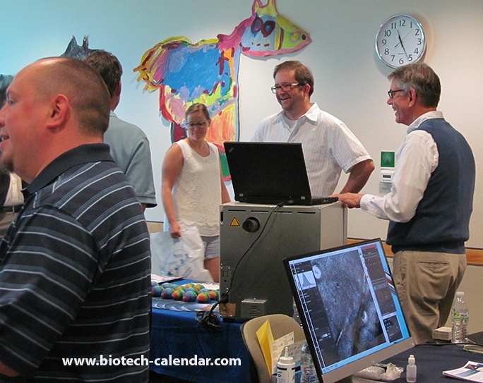 Lab researchers spekaing with an exhibitor at the science tradeshow University of Wisconsin BioResearch Product Faire™ event
